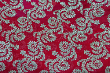 Dark red Georgette saree, floral pattern with beads embroidery. Close-up of elegant Indian fabric design background.