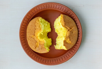 Delicious Chiffon cake, cut in half, on a clay plate. Fluffy and tasty, top view.