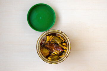 Delicious sweet and sour mango pickles in open glass jar on light wood, top view. Popular South and Southeast Asian delicacy.