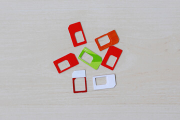 Assortment of SIM cards in various sizes scattered on a wooden surface, top view. Mobile technology, telecommunications, global connectivity, subscriber identity modules.