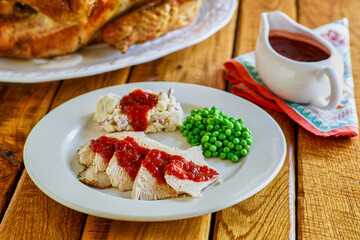 sliced turkey breast, mashed potatoes, and steamed peas with a spicy cranberry gravy