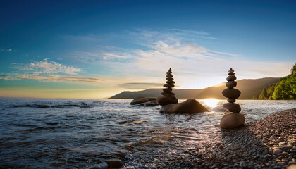 Serene landscape featuring stacked stones by tranquil lake at sunset, reflecting peaceful moment in nature