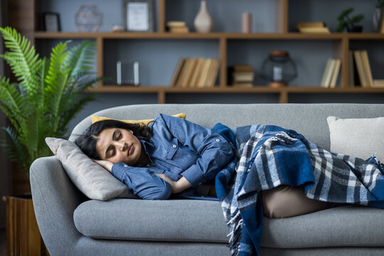 Young Muslim woman resting and sleeping at home on the sofa covered with a blanket