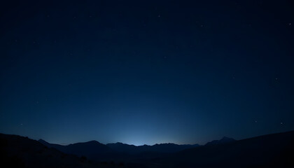 Dark mountains silhouette under starry sky with glowing horizon