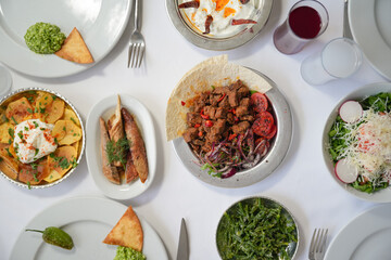 Traditional Turkish Meze Table with Liver, Fried Potatoes, Aegean Greens, Yogurt and Salad on a White Cloth