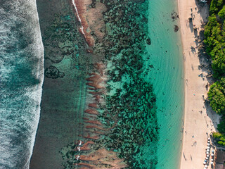 Bright turquoise waters lap the sandy shores of Melasti Beach in the summer sun in Bali.