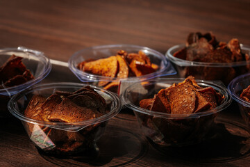 Multiple cups filled with crispy rye bread chips, seasoned with spices and arranged on a wooden table for serving or snacking.
