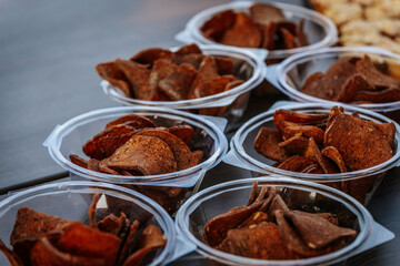 Multiple cups filled with crispy rye bread chips, seasoned with spices and arranged on a wooden table for serving or snacking.