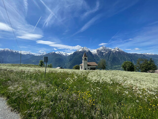 aerial view of Italian Alps, snow-capped ridges in the background, blue sky and white clouds