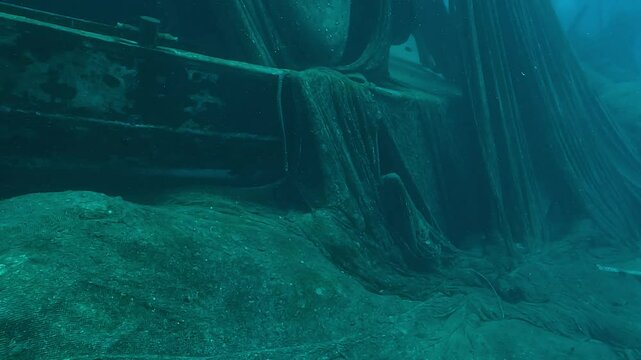 Ghost fishing nets drape from the mast of a sunken trawler in the Red Sea. Underwater view, mid-range shot. Check my portfolio for more shipwreck footage.
