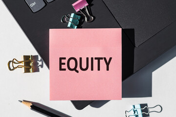 Pink Sticky Note With The Word Equity On Top of Laptop