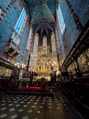 Interior of St. Mary's Basilica in Kraków, featuring the iconic wooden altarpiece by Veit Stoss, stunning stained-glass windows, and Gothic-style design. © Romy