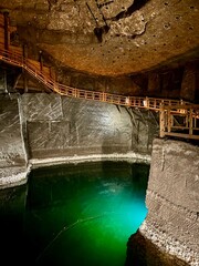 Mysterious underground lake in the Wieliczka Salt Mine with dramatic lighting and wooden walkways...