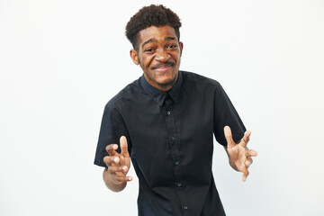 Smiling Black man expressing joy with open arms, wearing a stylish black shirt against a clean...