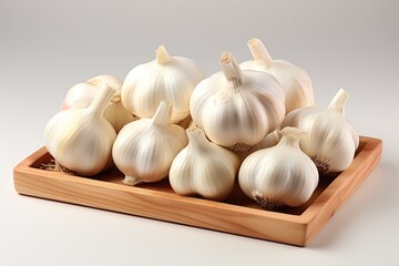 Several white garlics placed on a wooden tray on a white background.