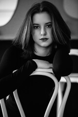 Black and white portrait of a young beautiful dark-haired girl in a low key.