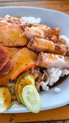 Red pork and crispy pork on rice in a blue plate on a wooden  table in Thailand