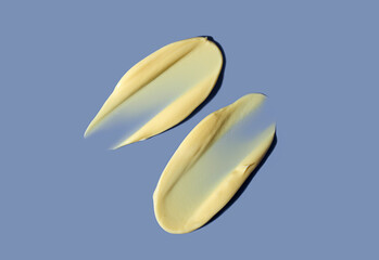 Yellow cosmetic smear of cream texture on a blue background. Skin care.