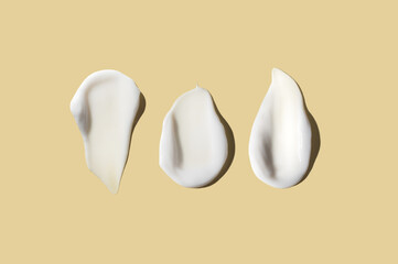 Cosmetic smear of cream texture on pastel yellow background. Three different smear of cream texture. Skin care.