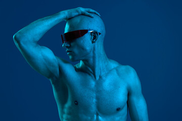 Athletic man striking a pose wearing sleek sunglasses, showcasing a strong physique against a...