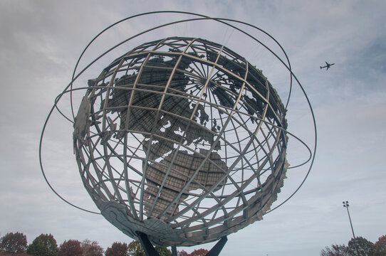A passenger jet flying near the unisphere in queens new york on a cloudy autumn day