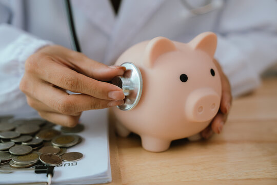 Doctor using stethoscope to examine a piggy bank, symbolizing the savings in medical care and financial health. - Powered by Adobe
