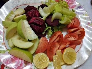 Fresh sliced fruits and vegetables on a floral plate