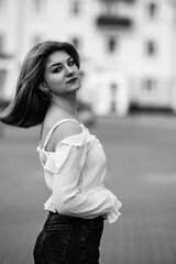 Fototapeta premium Black and white portrait of a young beautiful long-haired girl outdoors.