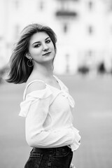 Black and white portrait of a young beautiful long-haired girl outdoors.