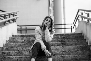 Black and white portrait of a young beautiful long-haired girl outdoors.