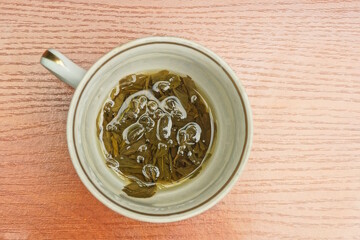 one cup full of green tea drink stands on the brown table on a summer street