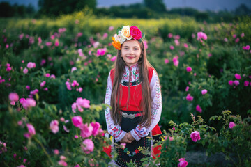 Portrait of beautiful bulgarian girl in ethnic folklore clothes during harvesting blooming...