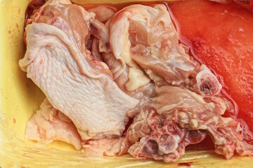 pieces of raw red chicken meat in a yellow plate