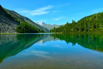 Fototapeta premium View of Karwassersee alpine lake with a coniferous forest at the shore and a reflection in the water in High Tauern, Central Eastern Alps, Austria