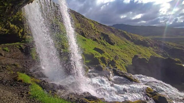 Witness the breathtaking beauty of Selvallafoss waterfall flowing down rocky cliffs in Iceland, surrounded by lush greenery and dramatic Icelandic terrain.