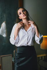 Indoors portrait of attractive sad girl dressed in black skirt and white blouse. Cute young woman...