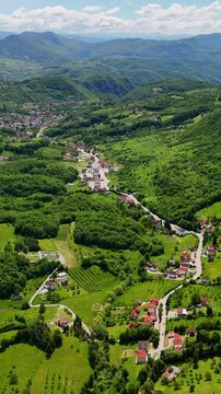 Vertical aerial view of a picturesque landscape with green hills, traditional villages and blooming fields in Bosnia and Herzegovina. 