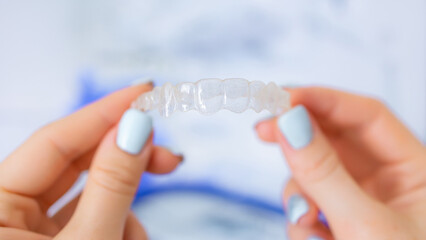 Close-up of hands holding a clear aligner for orthodontic teeth correction