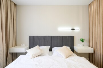 modern bedroom featuring a bed with a gray headboard, white linens, floating bedside tables, and neutral-toned decor