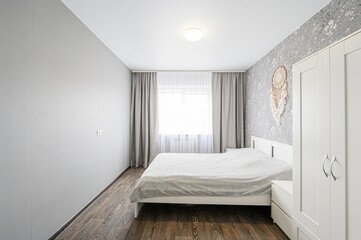 neat bedroom with a white bed, gray walls, floral wallpaper, curtains, and a white wardrobe