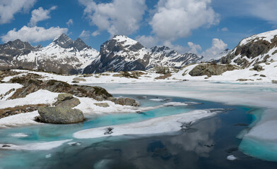 thawing lake with view of snow-capped mountains