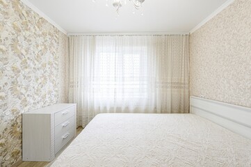 bright bedroom with floral wallpaper, a white bed, curtains, a chandelier, and a white dresser