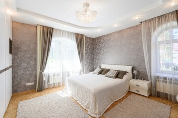 stylish bedroom with a bed, patterned walls, elegant curtains, and a crystal chandelier. Neutral color scheme for a calming ambiance