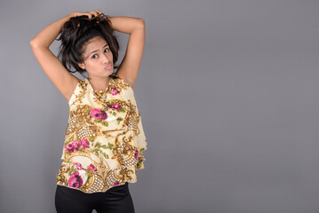 A charming young woman wearing a floral patterned top, black leggings and black heels, posing with...
