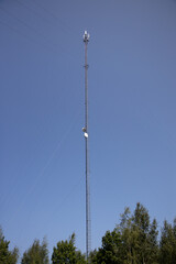 Tall Communication Tower with Satellite Dishes Against a Blue Sky
