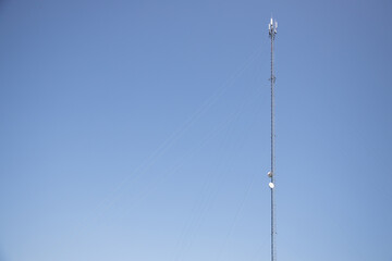 Tall Communication Tower with Satellite Dishes Against a Blue Sky