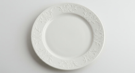 A white ceramic dinner plate with embossed border design, top view.