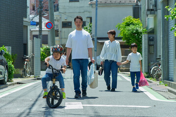 晴天の住宅街を歩く家族4人