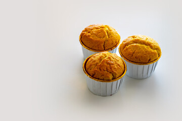 Three golden muffins resting on a white surface