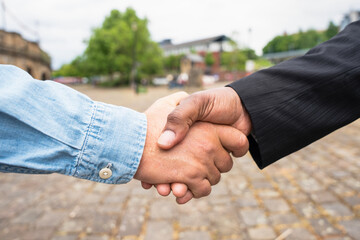 Handshake between two individuals in a public outdoor setting showcasing cooperation and agreement during daytime in an urban environment